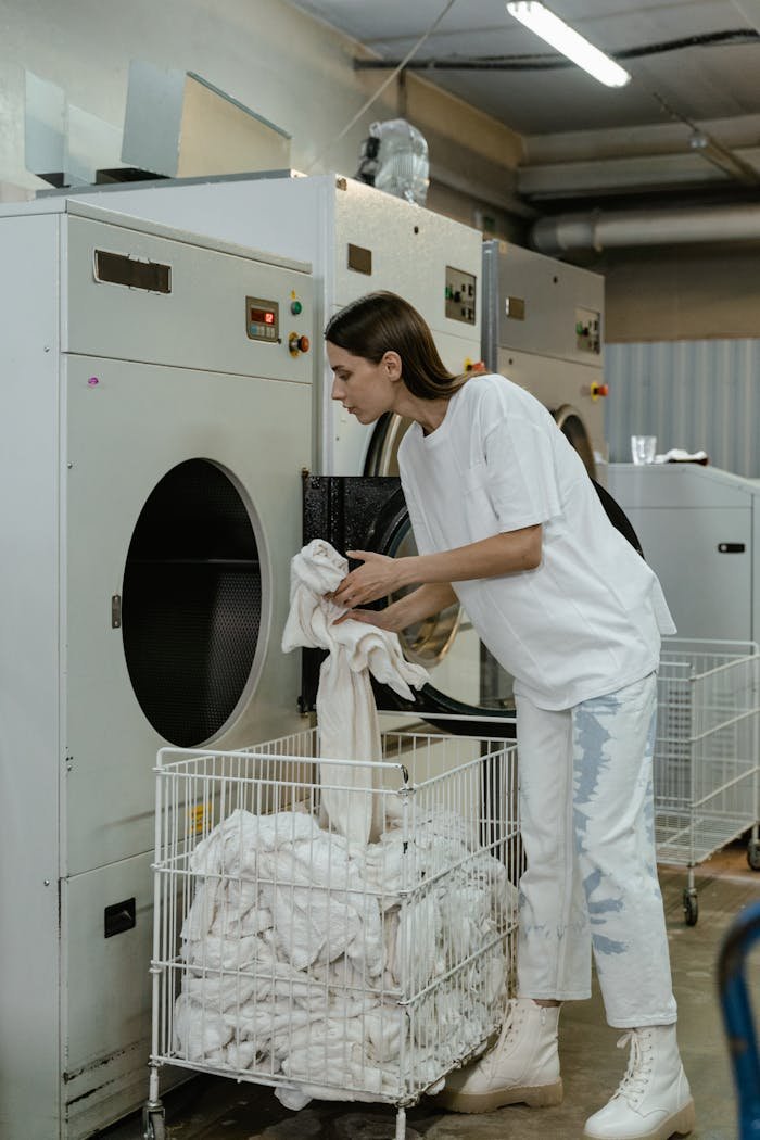gallery-5 A woman in a laundry facility managing industrial washing machines, focusing on service and efficiency.